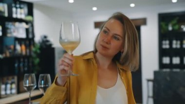 Kadın şaraphanede beyaz şarap tadıyor..