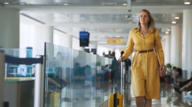Woman with suitcase walking in airport terminal.