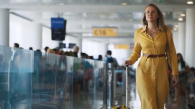 Woman with suitcase walking in airport terminal.