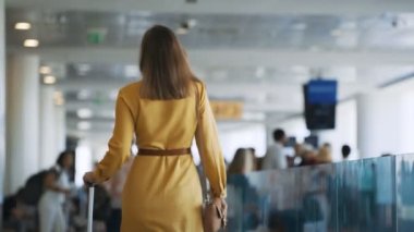 Woman walking in airport terminal. Back view.