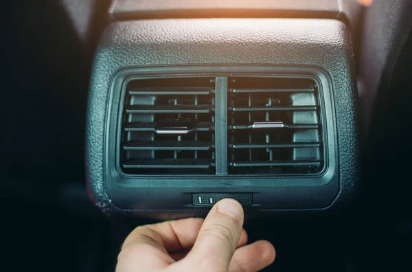 Man adjusting air conditioner inside the car.