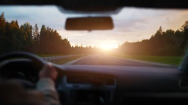Driving car in summertime on the sunset.