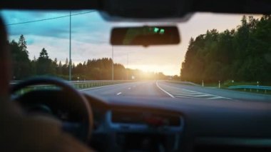 Driving car in summertime on the sunset.