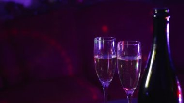 Bottle of champagne and two glasses in night club.