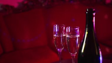 Bottle of champagne and two glasses in night club.
