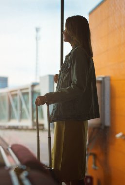 Woman with luggage waiting for the flight in airport.