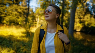Woman tourist with backpack exploring forest.