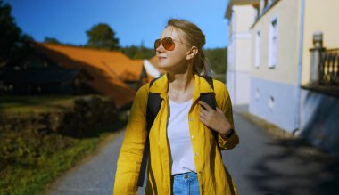 Woman tourist with backpack walking in the village.