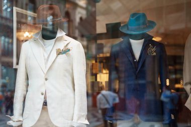 Men mannequins advertise summer clothes behind glass.