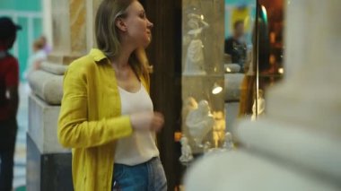 Kadın turist hediyelik eşyalarla dükkanın camına bakıyor..