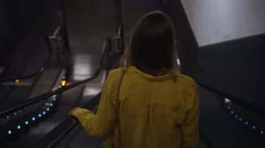 Metroda bir yürüyen merdiven kullanan kadın.