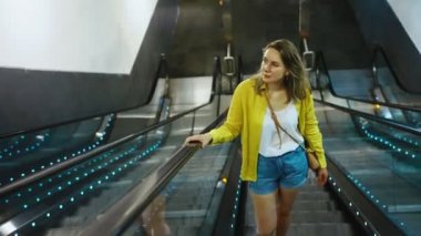 Metroda bir yürüyen merdiven kullanan kadın.