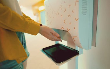 Woman uses automatic hand sanitizer when entering a mall.