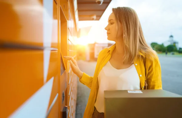 Woman sending mail via automated self-service post terminal machine.