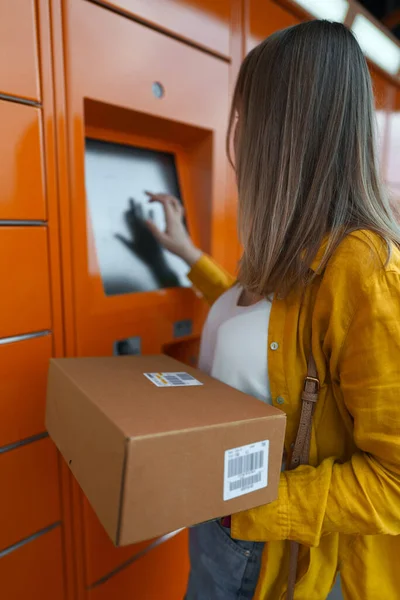 Woman sending mail via automated self-service post terminal machine.