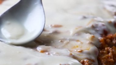 The spoon spreads the bechamel sauce. Cooking lasagna.