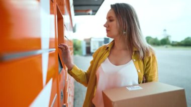 Woman sending mail via automated self-service post terminal machine.