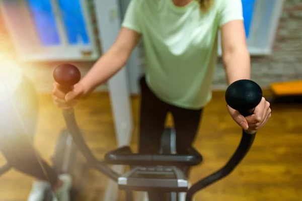 Woman training on elliptical trainer in gym