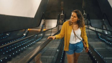 Metroda bir yürüyen merdiven kullanan kadın.