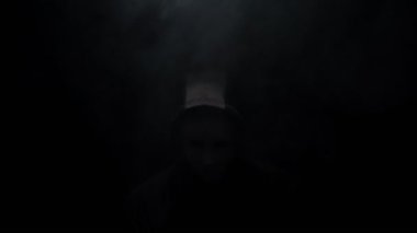 Siyah arka planda kapüşonlu maskeli bir adam..