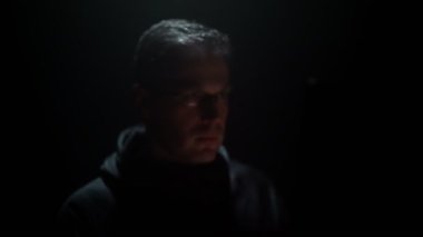 Kapüşonlu adam bilgisayarda çalışıyor..