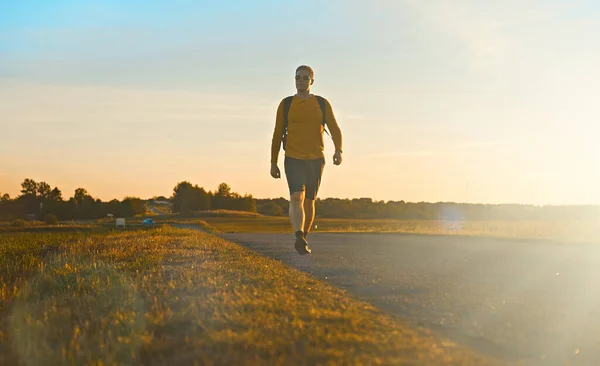 Mann Mit Rucksack Läuft Bei Sonnenuntergang Die Straße Entlang — Stockfoto