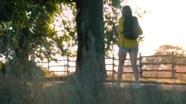 Woman tourist with backpack walking in the countryside.
