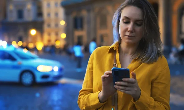 Woman with smartphone lost in the evening city.