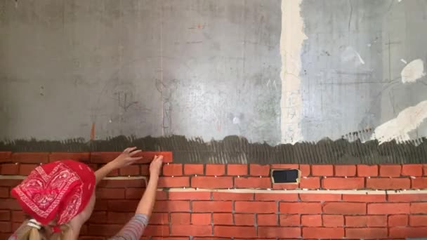 Час відновлення будинку. жінка приклеює цеглу до стіни — стокове відео