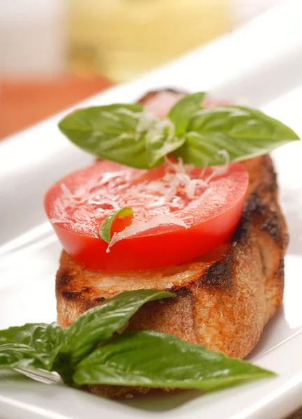 Bruschetta gegarneerd met verse tomaat en basilicum — Stockfoto