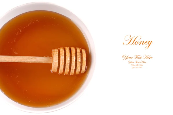 Closeup of a bowl of amber honey with a honey wand — Stock Photo, Image