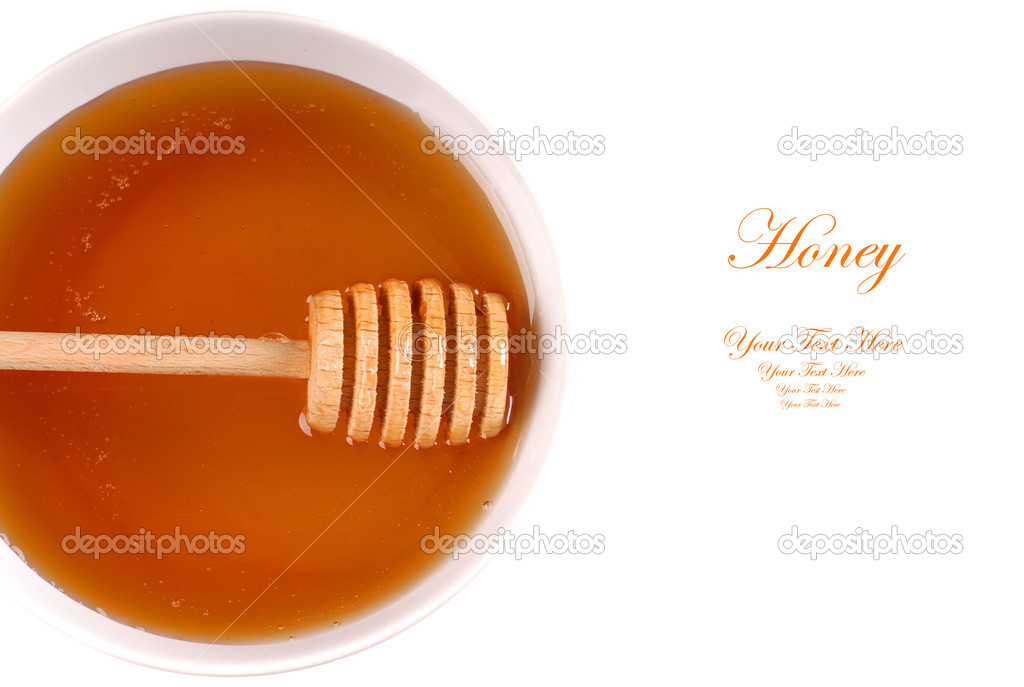 Closeup of a bowl of amber honey with a honey wand