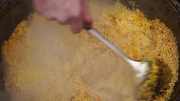 Reis im Kessel beim Kochen von Pilaf auf einem traditionellen asiatischen Ofen. — Stockvideo
