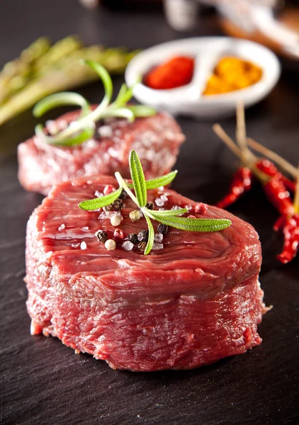 Syrové čerstvé hovězí steaky na černém kameni — Stock fotografie