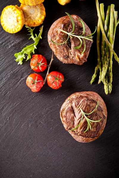 Fresh beef steaks on black stone — Stock Photo, Image
