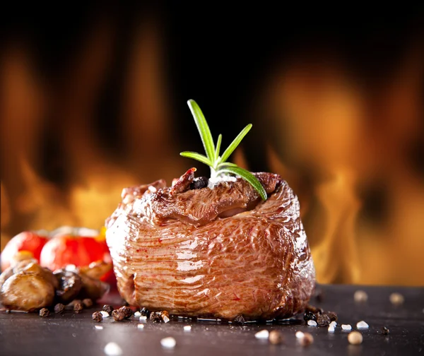 Fresh beef steak on black stone and fire — Stock Photo, Image