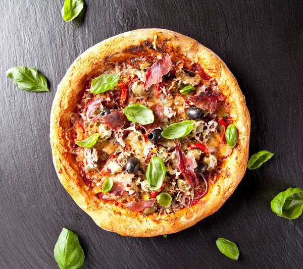 Fresh italian pizza served on black stone — Stock Photo, Image