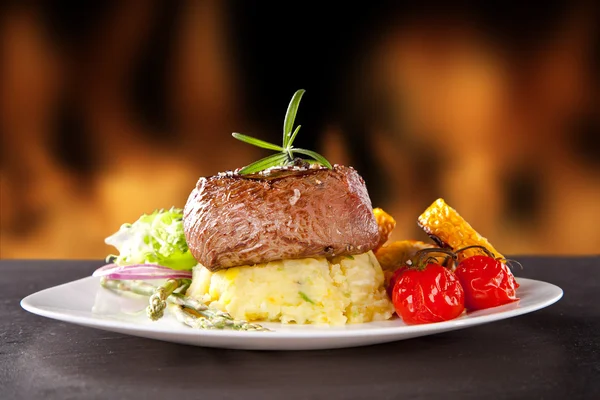 Fresh beef steak on black stone and fire — Stock Photo, Image