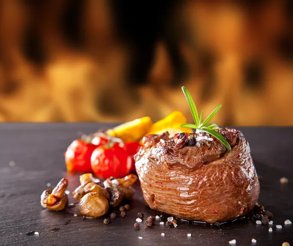 Bistecca di manzo fresca su pietra nera e fuoco — Foto Stock