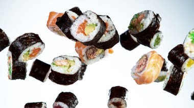 Beyaz arka planda uçan suşi parçalarının hareketlerini dondur. Geleneksel Japon yemeklerini uçurma kavramı. Stüdyo çekimi, koyu arkaplan.