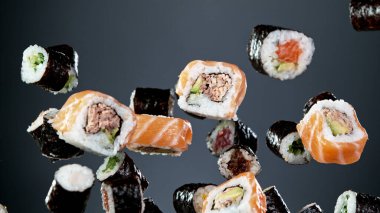 Siyah arka planda uçan suşi parçalarının hareketlerini dondur. Geleneksel Japon yemeklerini uçurma kavramı. Stüdyo çekimi, koyu arkaplan.
