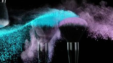 Uçan renkli tozlu makyaj fırçalarının süper yavaş çekimi. Yüksek hızlı sinema kamerası, 1000fps.