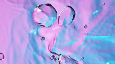 Neon ışıklarıyla aydınlatılan su damlalarının süper yavaş akışı. Yüksek hızlı sinema kamerası, 1000 fps..