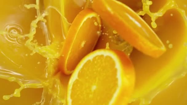 Superlangzame beweging van sinaasappelschijfjes die in sap vallen. — Stockvideo