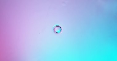 Neon ışıklarıyla aydınlatılan damlayan su damlasının süper yavaş çekimi. Yüksek hızlı sinema kamerası, 1000 fps..