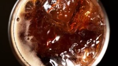 Buz küpünün kola içeceğine düşmesi çok yavaş bir hareket, üst manzara. Yüksek hızlı sinema kamerası, 1000 fps. Hız rampası etkisi.