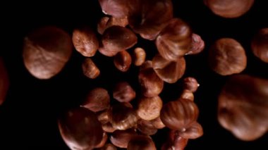 Düşen fındıkların süper yavaş çekimi, geniş süper makro çekim. Siyah arka planda izole edilmiş. Yüksek hızlı sinema kamerası, 1000fps.
