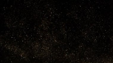 Siyah zemin üzerinde ışıldayan altın parçacıkların süper yavaş çekimi. Sığ odak derinliği. Yüksek hızlı sinema kamerası, 1000 fps..