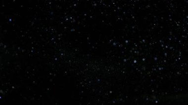 Siyah arkaplanda ışıldayan mavi parçacıkların süper yavaş çekimi. Sığ odak derinliği. Yüksek hızlı sinema kamerası, 1000 fps..