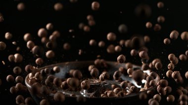 Kavrulmuş kahve çekirdeklerinin dondurucu hareketi. Stüdyo fotoğrafı, siyah arkaplanda izole edilmiş..